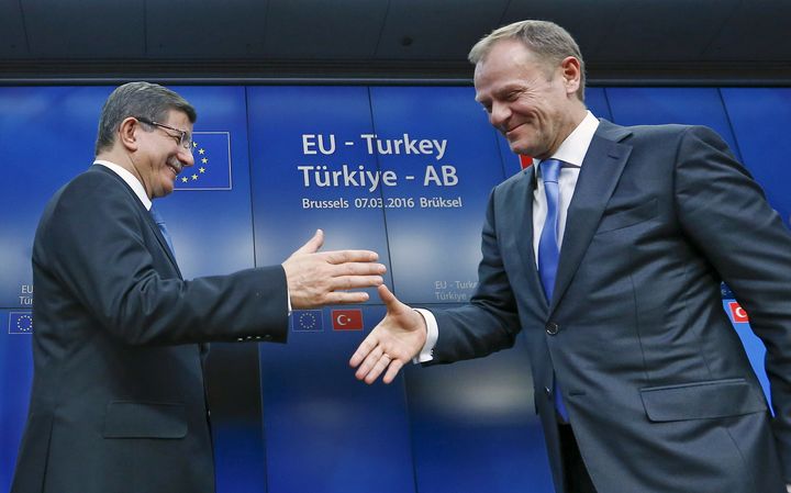 Turkish Prime Minister Ahmet Davutoglu and European Council President Donald Tusk shake hands at the end of an EU-Turkey summit in Brussels. Under the deal, the European Union will speed up payments to Turkey and "re-energize" Turkey's application to become an EU member.