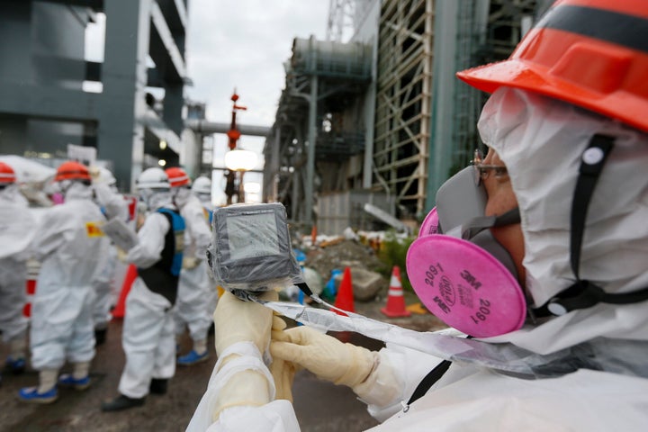 A Tokyo Electric Power Co. employee measures radiation levels as workers conduct operations to construct an underground ice w