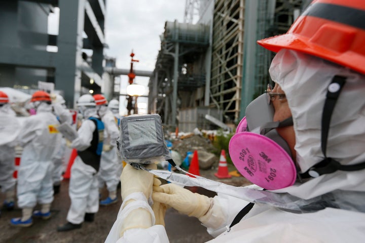 A Tokyo Electric Power Co. employee measures radiation levels as workers conduct operations to construct an underground ice wall at the tsunami-crippled Fukushima Daiichi nuclear power plant in Fukushima Prefecture.