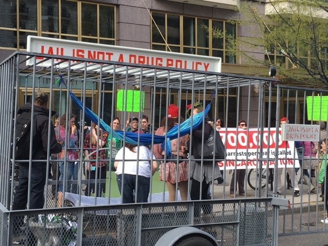 Cannabis activists gather around a mock jail cell.