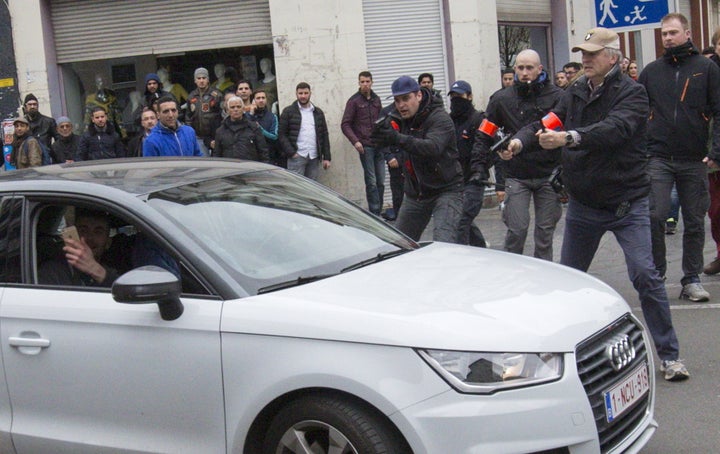 A passenger in the Audi can be seen taking a photo on his mobile phone as the car passes through the police barricade 