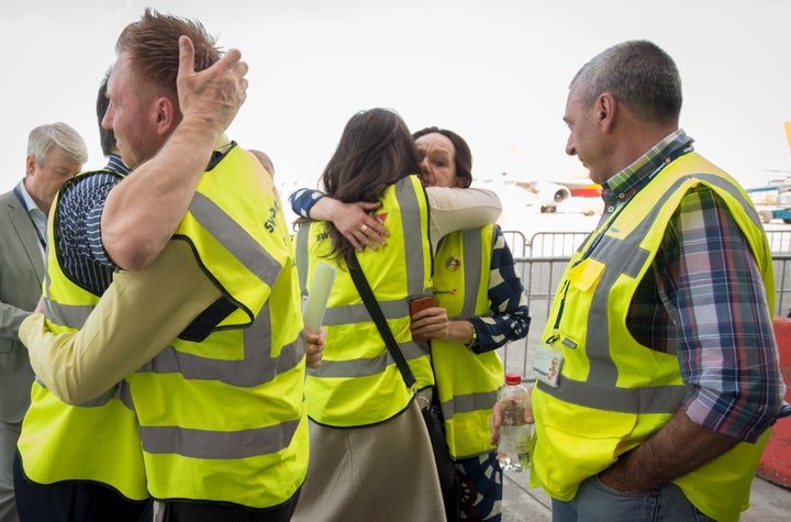 Brussels Airport staff hug as the first plane takes off from Brussels Airport, which partially re-opened following a bomb bla