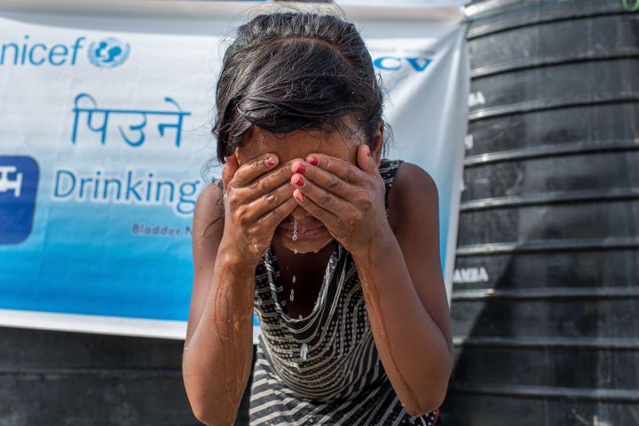 A young girl washes her face at one of the water taps set up inside the Chuchepati displacement camp on August 13, 2015 in Kathmandu, Nepal