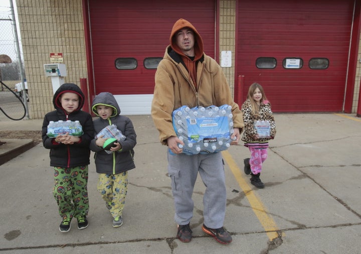 Flint resident Jerry Adkisson and his children Jayden, Austin and Amiya carry bottled water they picked up from a fire station in Flint, Feb. 7, 2016.