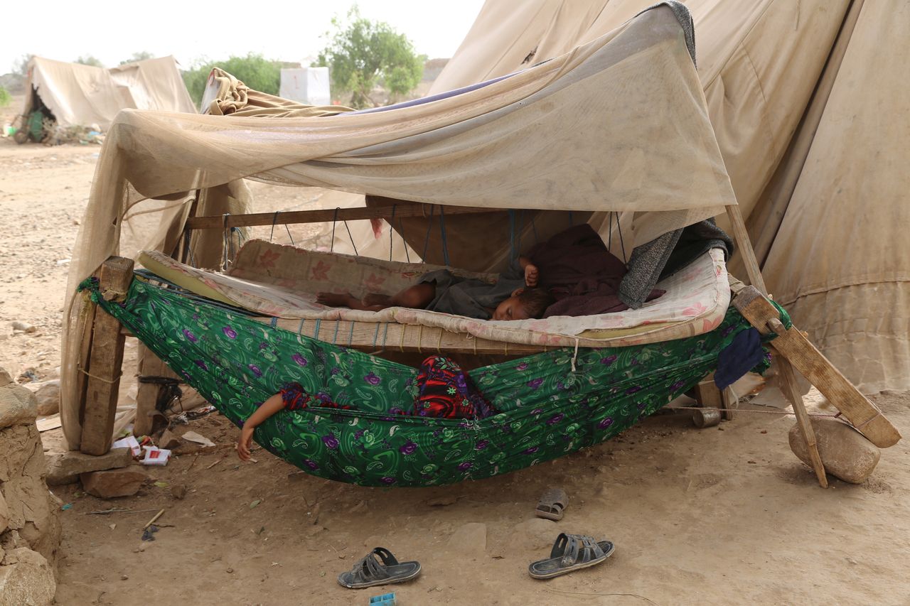 A man and a boy sleep outside a tent at the Shawqaba camp. 