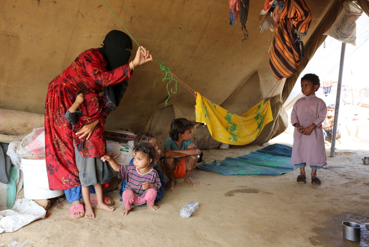 A woman and children are pictured in their tent at the Shawqaba camp.