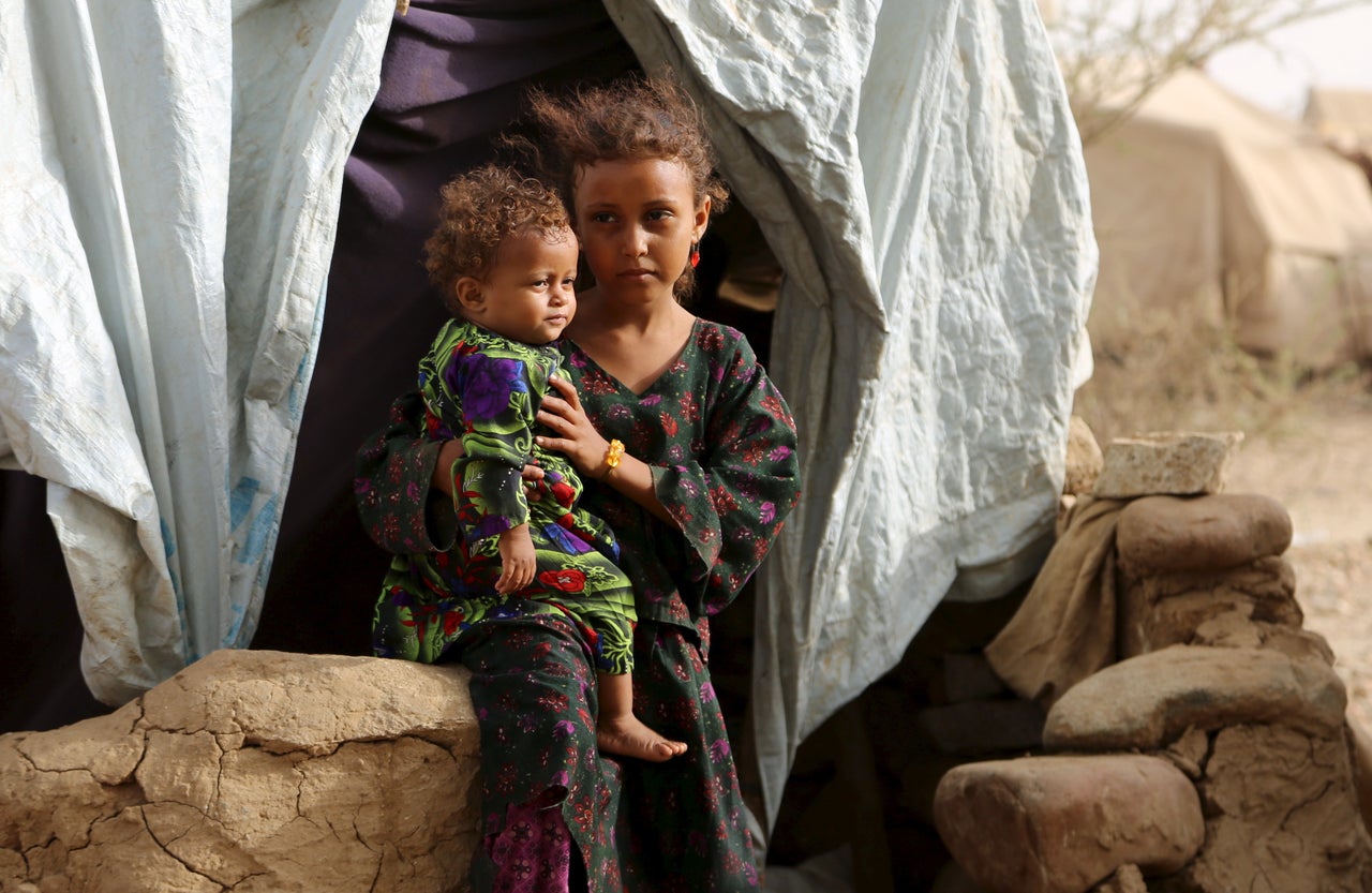 A girl holds her sister outside their family's hut. Around 400 families live in the camp.