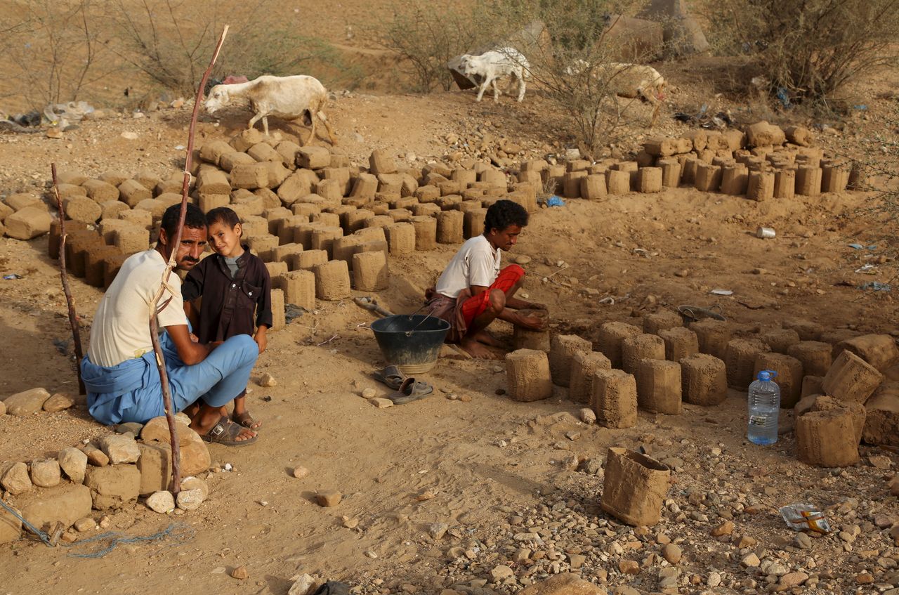 People prepare mud bricks to build a hut at the camp. 