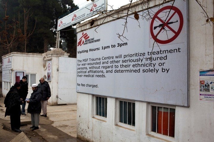 Thomas recalls "the touch of desperate people pulling at my clothes to get my attention begging me to help their injured loved ones" in the week leading up to the airstrike. A sign shows MSF's no-weapons and no-fee policies outside the Kunduz hospital.