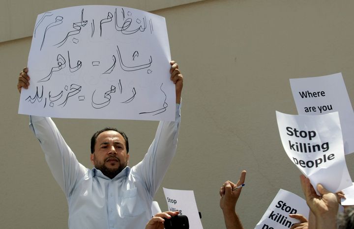 Syrians hold banners condemning Syrian president Bashar Assad and his allies, including billionaire cousin Rami Makhlouf, who owned offshore companies set up and run by Mossack Fonseca.