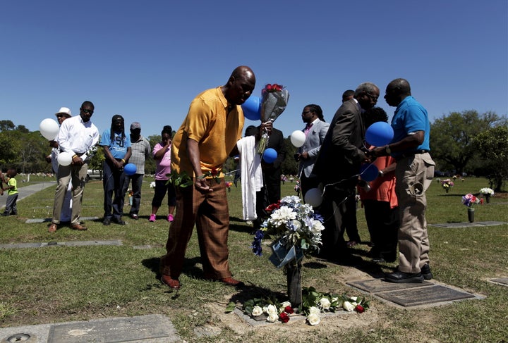 Gary Butts, family friend of the late Walter Scott, lays a rose at the gravesite as relatives and friends gathered to remembe