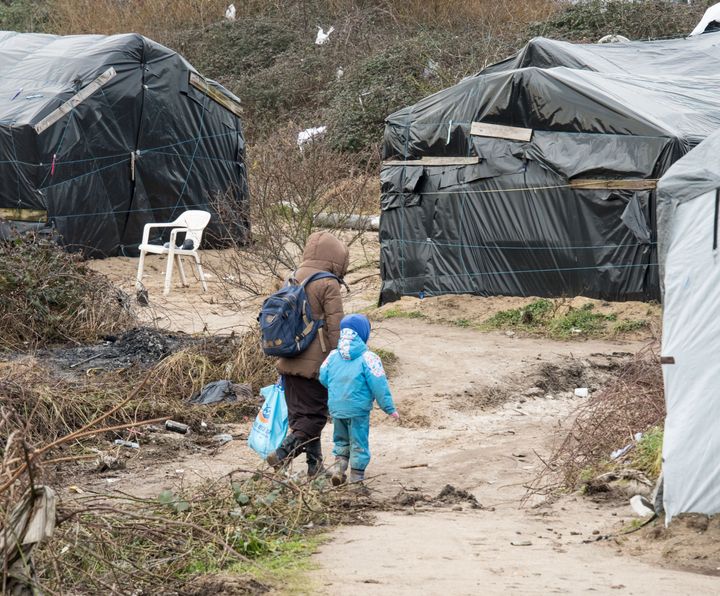 A woman walks with her child in the Calais 'Jungle' 