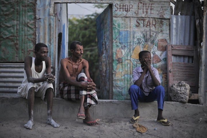 A father and his two sons watch a security operation in Mogadishu in 2013. Somalia will hold elections, but not by popular vote, later this year.