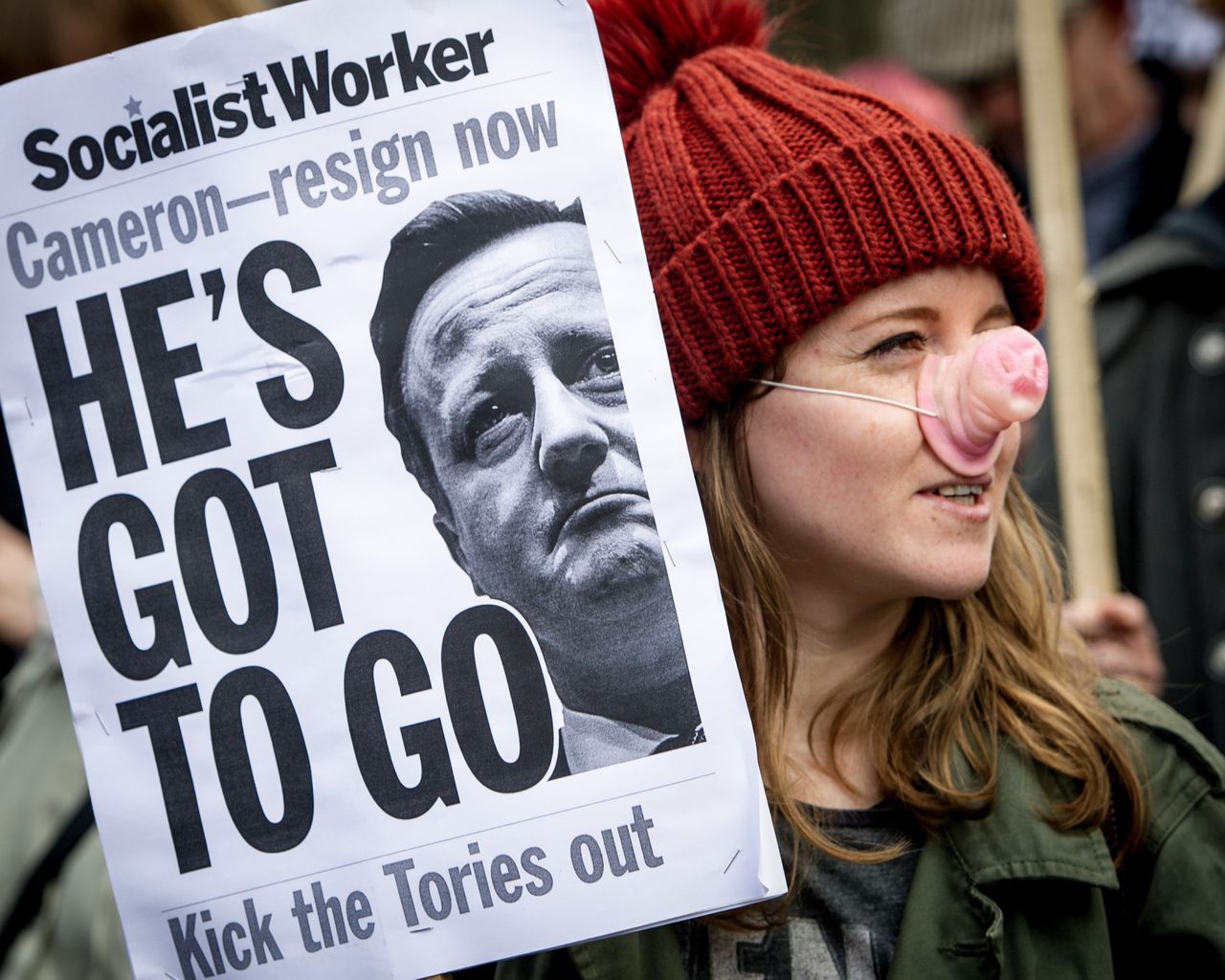 'He's Got To Go' placard held by a protestor wearing a pig's nose