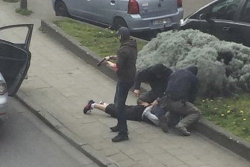 Police officers detain a suspect during a raid in which Mohamed Abrini was arrested in Anderlecht, near Brussels. Police raid