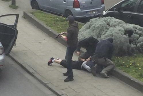 Police officers detain a suspect during a raid in which Mohamed Abrini was arrested in Anderlecht, near Brussels. Police raided another Brussels apartment on Saturday, but made no arrests.