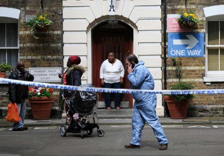 A police forensic officer walks past residents