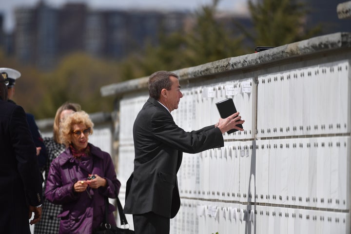 Bill Sheppard places Andrew Moore's cremated remains in a niche at Arlington National Cemetery on Friday.