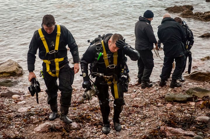 Police divers exit the water at Anstey's Cove in Torquay, Devon