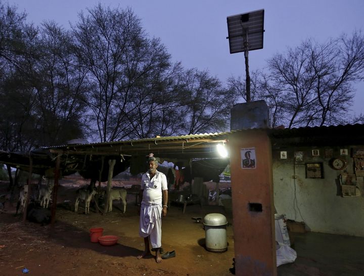 Last year, India faced a 3.6% deficit in peak-hour energy supply, and over 280 million people in the country still don't have access to electricity. A villager poses next to a solar-powered lamp in Gandhinagar, India.