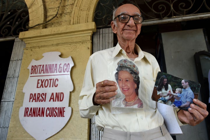 Kohinoor, 93, an ardent fan of the British royal family, poses with photos of Queen Elizabeth, and the duke and duchess of Cambridge outside the Britannia & Co.