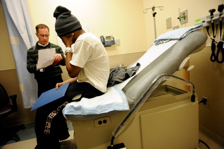 Attending physician John Krotchko examines Larry Richardson at the Denver Heath Adult Urgent Care Clinic in Denver, CO. Richardson was being seen for his asthma, as well as chronic joint pain. Without insurance Richardson says he goes to Denver Health when he needs medical attention. The hospital is partially compensated for the treatment by CICP, Colorado Indigent Care Program. Richardson,a construction worker, has not been able to find steady work for the past year - due to his condition. The state Medicaid office enrolls 3,000 new members a month for health aid to low-income residents, a rate a spokeswoman calls 'astronomical' and unprecedented in the program's history. Denver Health, the prime urban outlet for residents lacking health insurance, saw 1,500 new uninsured patients in December, eight more patients a day than a year ago. (Craig F. Walker/The Denver Post) (Photo By Craig F. Walker/The Denver Post via Getty Images)