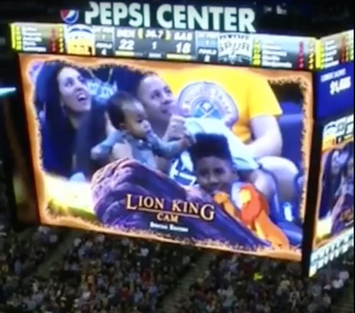 A baby is seen being lifted up like Simba from Disney's "Lion King" movie during a Denver Nuggets basketball game.
