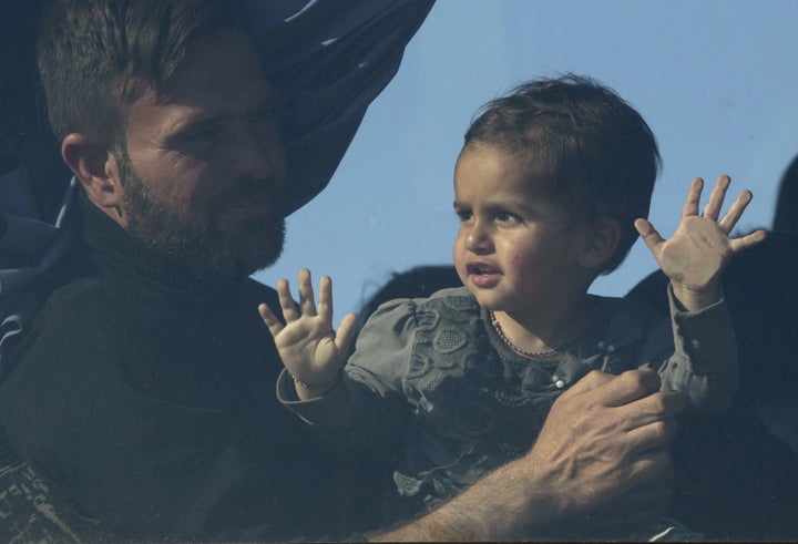 A man and a child are seen through a window of a bus bound for another camp in central Greece. About 12,000 migrants and refugees are stranded at the Greek-Macedonian border.