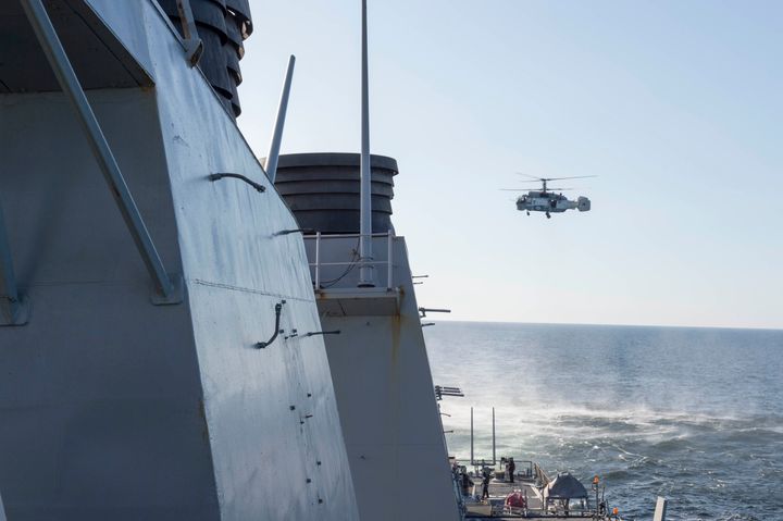 A Russian Kamov KA-27 HELIX helicopter flies low-level passes near the Arleigh Burke-class guided missile destroyer USS Donald Cook