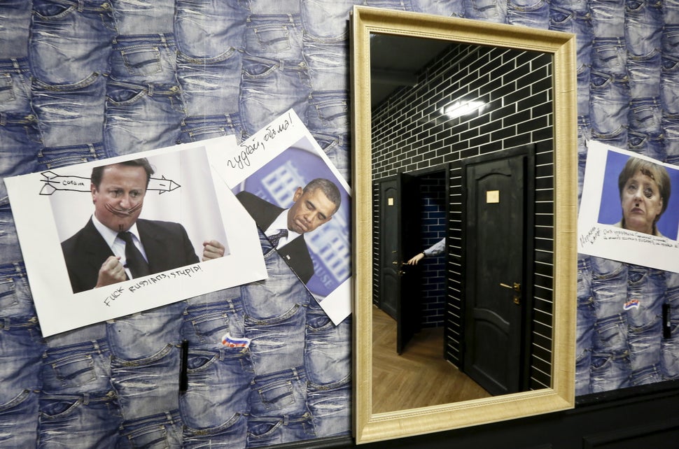 Photos of U.K. Prime Minister David Cameron, Obama and German Chancellor Angela Merkel line the bathroom walls. These gi