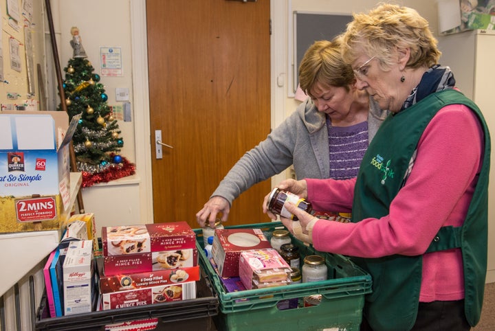 Volunteers collect food from shelves to fill a client's voucher request at a food bank in Liverpool