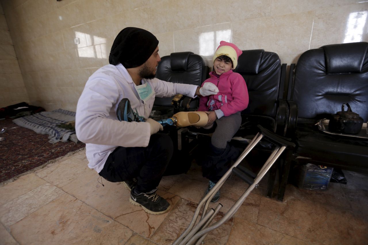 Two technicians run a mobile clinic that makes and fits prosthetic limbs for victims who had lost their limbs in the ongoing Syrian conflict. Amjad Hajj Khamis fits an artificial limb on 9-year-old Salma, who had lost her leg.