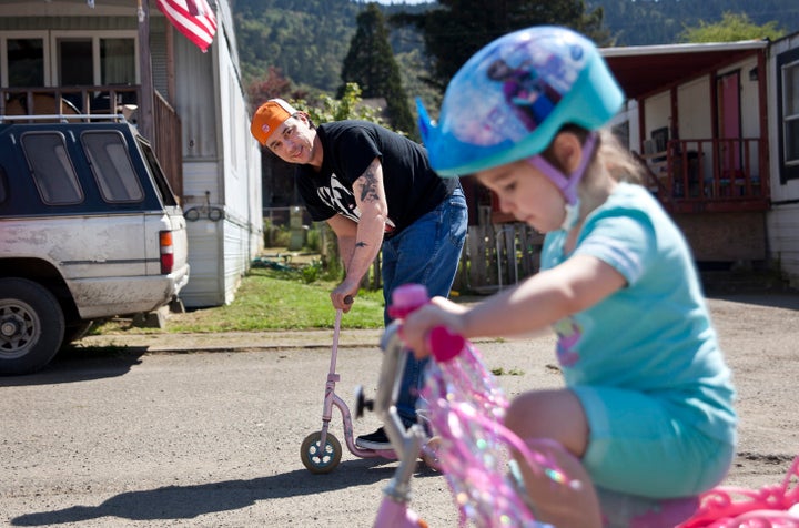 Bryan Thouvenel rides on a scooter while watching his daughter Harmony, 5, on her bike in front of their house in Myrtle Creek, Saturday April 3, 2016. Thouvenel and Harmony were recently reunited after a three year separation.