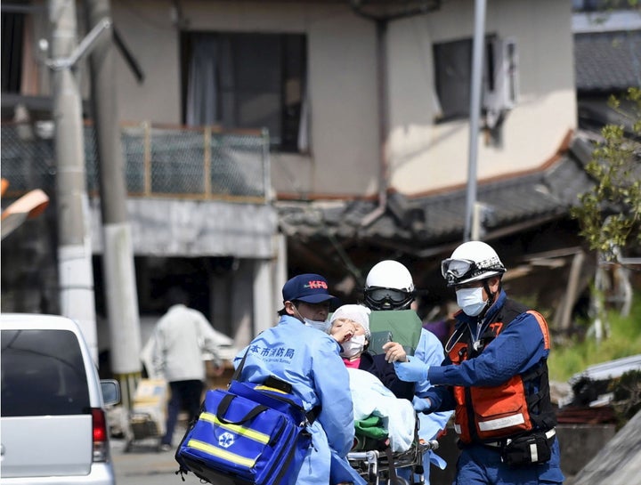 An injured person is carried by rescuers near a damaged house caused by an earthquake in Mashiki town, Kumamoto prefecture, southern Japan, in this photo taken by Kyodo April 15, 2016.