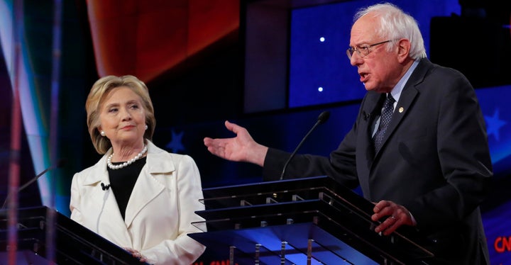 Democratic U.S. presidential candidate Hillary Clinton (L) listens to Sen. Bernie Sanders speak during a Democratic debate at the Brooklyn Navy Yard in New York April 14, 2016.