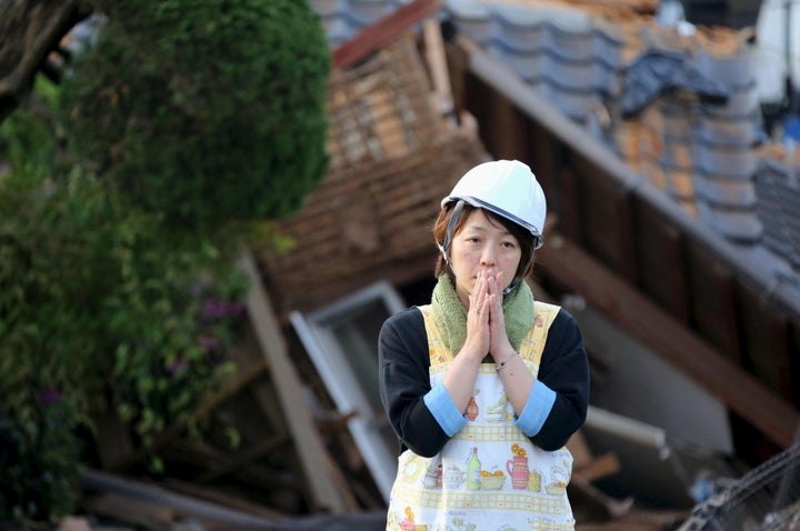 A woman reacts in front of collapsed house caused by an earthquake in Mashiki town. A 7.3 magnitude earthquake struck Japan on Saturday, killing at least 32 people and injuring about a thousand.