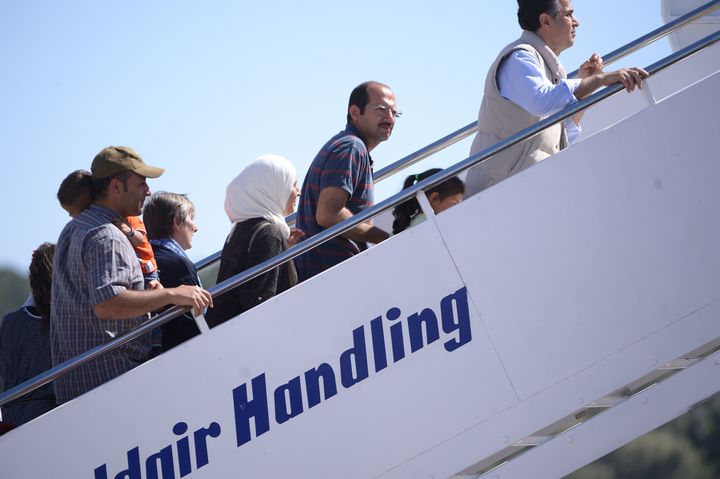 A group of Syrian refugees board a plane with Pope Francis.