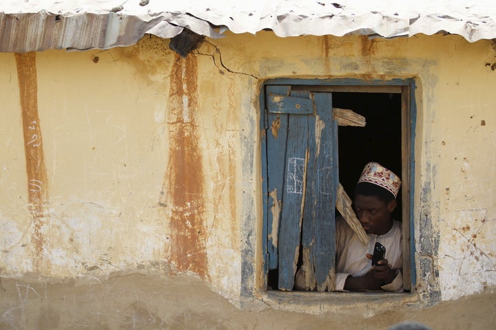 A boy looks through a broken window at a local Islamic school in Zaria, Kaduna state, Nigeria. Several former recruits depicted Boko Haram as a mafia-style organization, offering loans and demanding support.