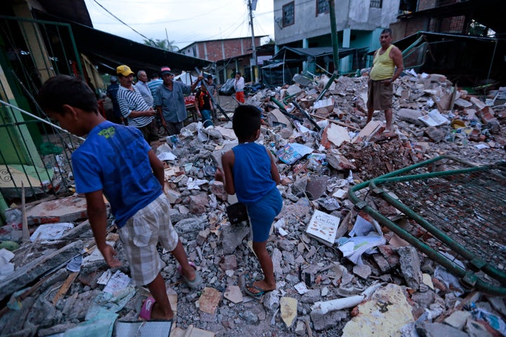 People stand amongst the rubble of fallen homes in Manta on April 17, 2016, after a powerful 7.8-magnitude earthquake struck Ecuador on April 16.