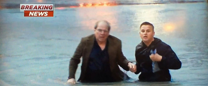 Reporter Steve Campion helps the man to his feet after his vehicle became submerged in Houston flood waters