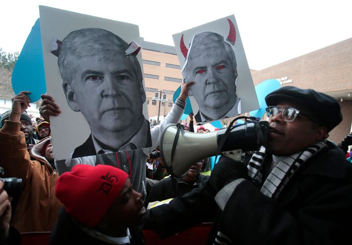 Demonstrators hold images of Michigan Gov. Rick Snyder outside the Democratic presidential debate in Flint, Michigan on March 6, 2016.