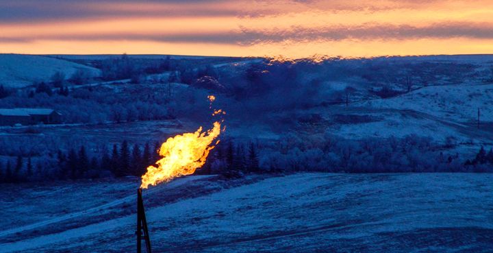 A natural gas flare on an oil well pad burns as the sun sets outside Watford City, North Dakota.