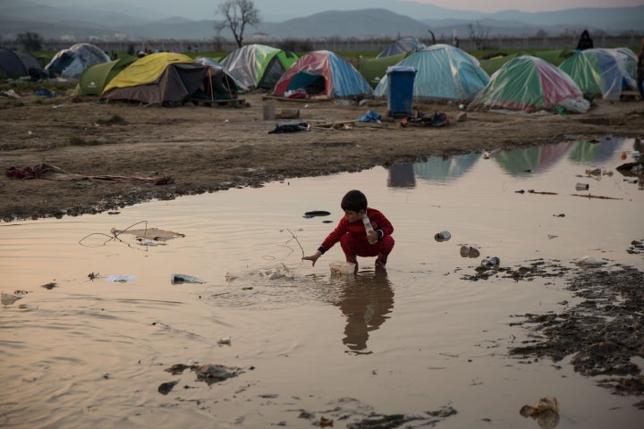 IDOMENI, GREECE - MARCH 19: Children play in puddles of rain water at the Idomeni refugee camp on the Greek Macedonia border