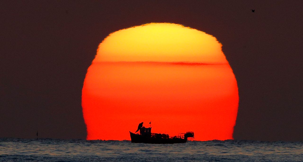 A lobster fisherman checks his pots as the sun rises over his small fishing boat in the North Sea near Whitley Bay in Northumberland.