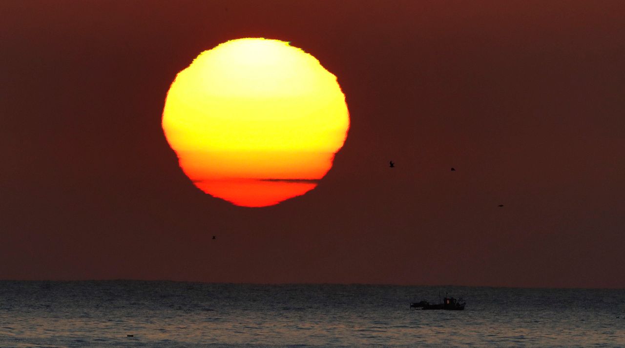 The sun rises over a small fishing boat.