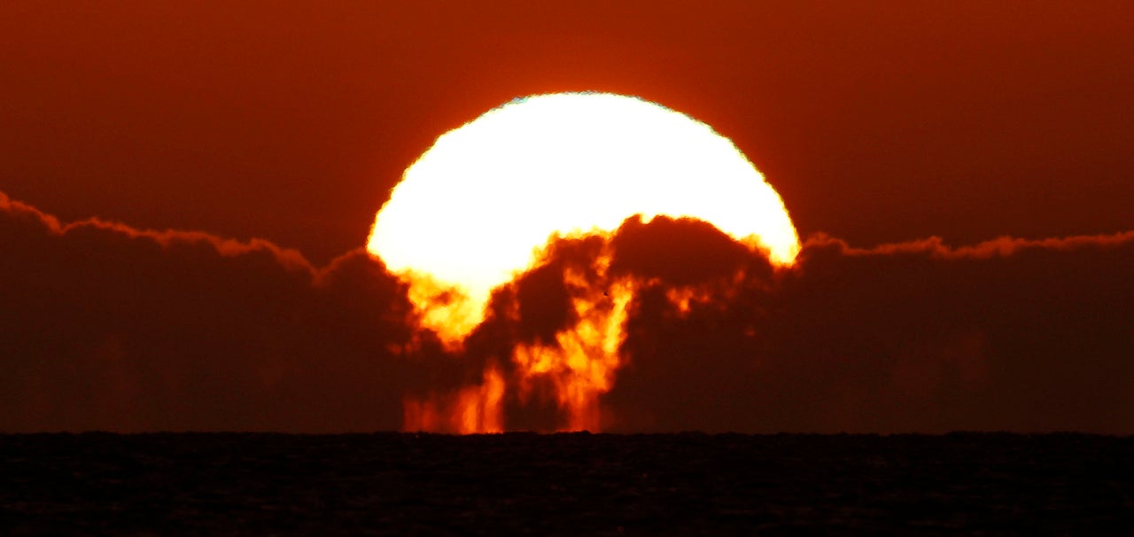 The sun rises between the clouds over the near Tynemouth beach, North Tyneside.