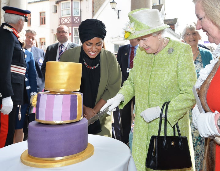 The Queen cuts a cake baked for her by Nadiya Hussain, the winner of the Great British Bake Off, a popular baking competition.