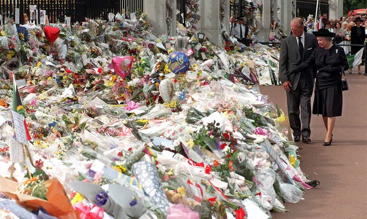 The Queen inspects the flowers left for Princess Diana following her death in 1997