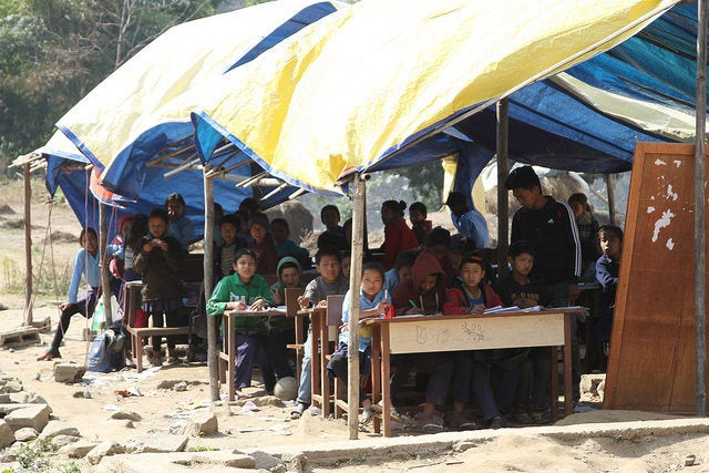 Children sit at their desks in a temporary learning center in Sindhupalchok. Volunteers have constructed makeshift classrooms, but they are in poor condition and vulnerable to bad weather.