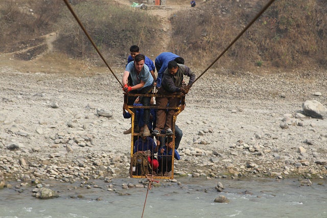 Schoolchildren cross a river in Dhading district with Christian Stephens, one of the producers of Theirworld's film. Many children have to undergo treacherous routes to reach the nearest school.